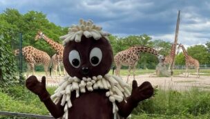 Der TV-Kobold Pittiplatsch im Tierpark Berlin mit Giraffen im Hintergrund